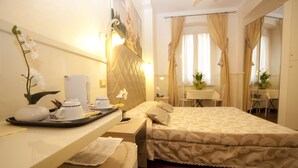A hotel room with a bed, a desk, a chair, a small table, and a mirror. - Le Suite di Via Ottaviano (Rome)
