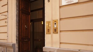 A hotel entrance with a wooden door, a number 6 sign, and a suite sign. - Le Suite di Via Ottaviano (Rome)