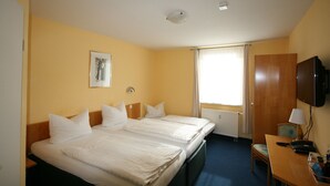 A hotel room with two beds, a desk with a chair, a television, and a window with curtains. - Hotel Classic Inn (Heidelberg)