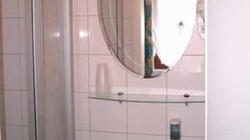 Un baño con cabina de ducha de vidrio, un lavabo y un espejo encima.