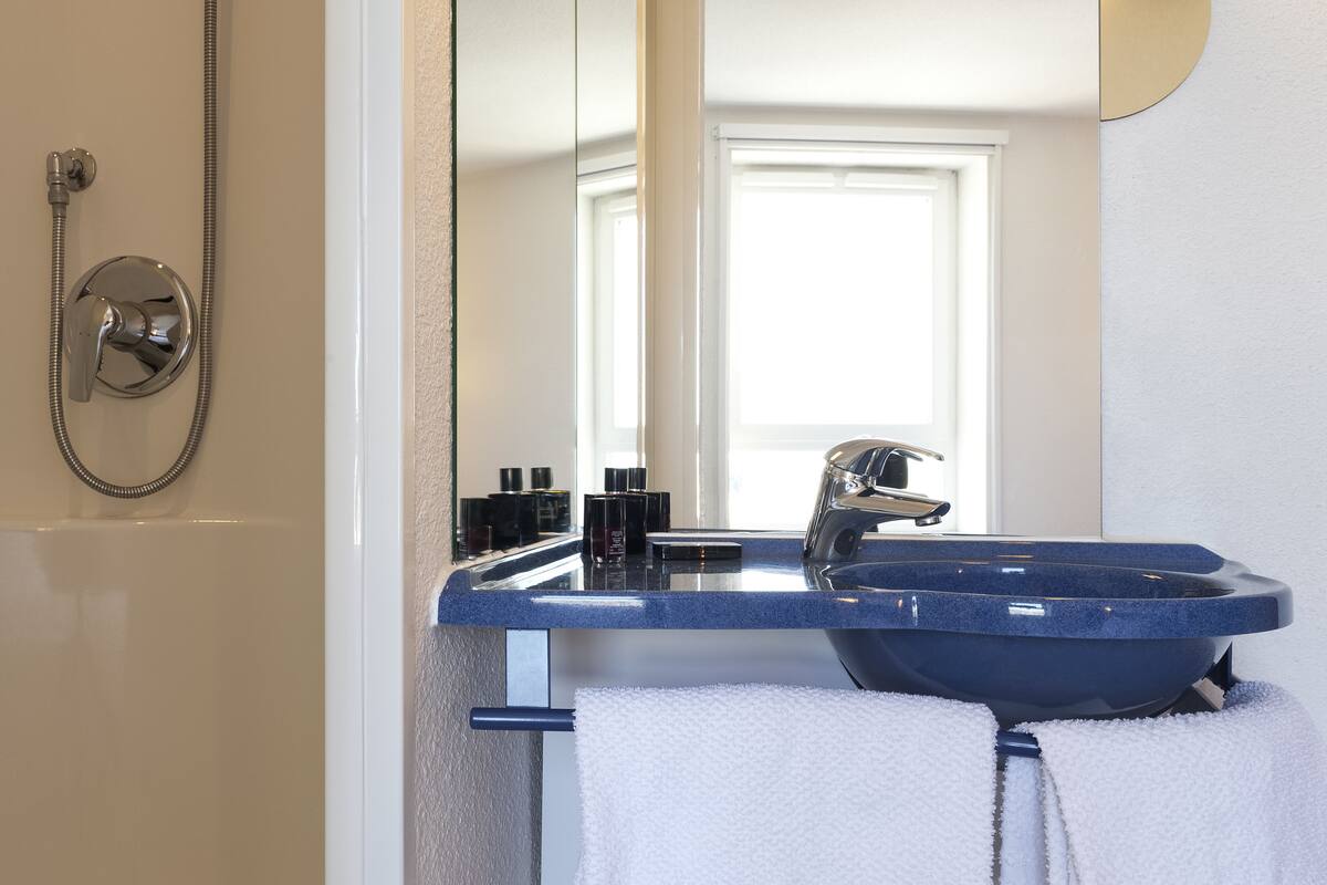 Un baño con un lavabo azul, un espejo y una ducha.