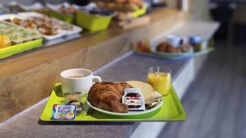 Ein Frühstücksbuffet mit verschiedenen Speisen und Getränken auf Tabletts.