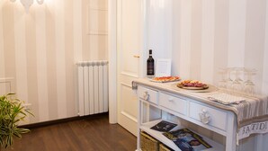 A room with a white striped wall, a radiator, a white door, a table with a pizza, wine glasses, and a bottle of wine. - B&B Mergellina (Naples)