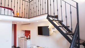 A modern interior with a dining area, kitchen, and a staircase with black railings. - B&B Mergellina (Naples)