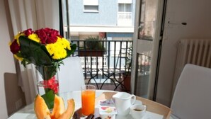 A breakfast table with a variety of food items, a vase of flowers, and a view of a building through a window. - Mirage (Lecce)