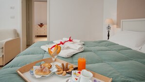 A neatly made bed with a green bedspread, a tray with breakfast items, and a bedside table with a lamp. - Mirage (Lecce)