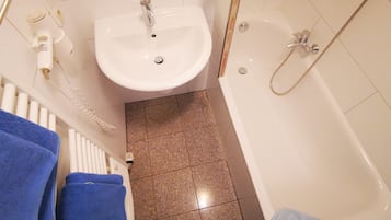 A bathroom with a white sink, a bathtub, and a shower. There are towels on the floor.
