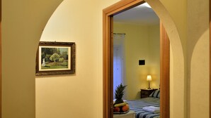 A hotel room with a bed, a nightstand, a lamp, and a framed painting on the wall.