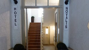 A hotel entrance with a red carpet leading to a staircase. There are two signs on either side of the entrance, one reading "HOTEL" and the other "NOVALIS". - Hotel Novalis (Berlin)