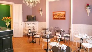 A dining area with multiple tables and chairs, a television on a cabinet, and a painting on the wall. - Hotel Maison Am Olivaer Platz (Berlin)