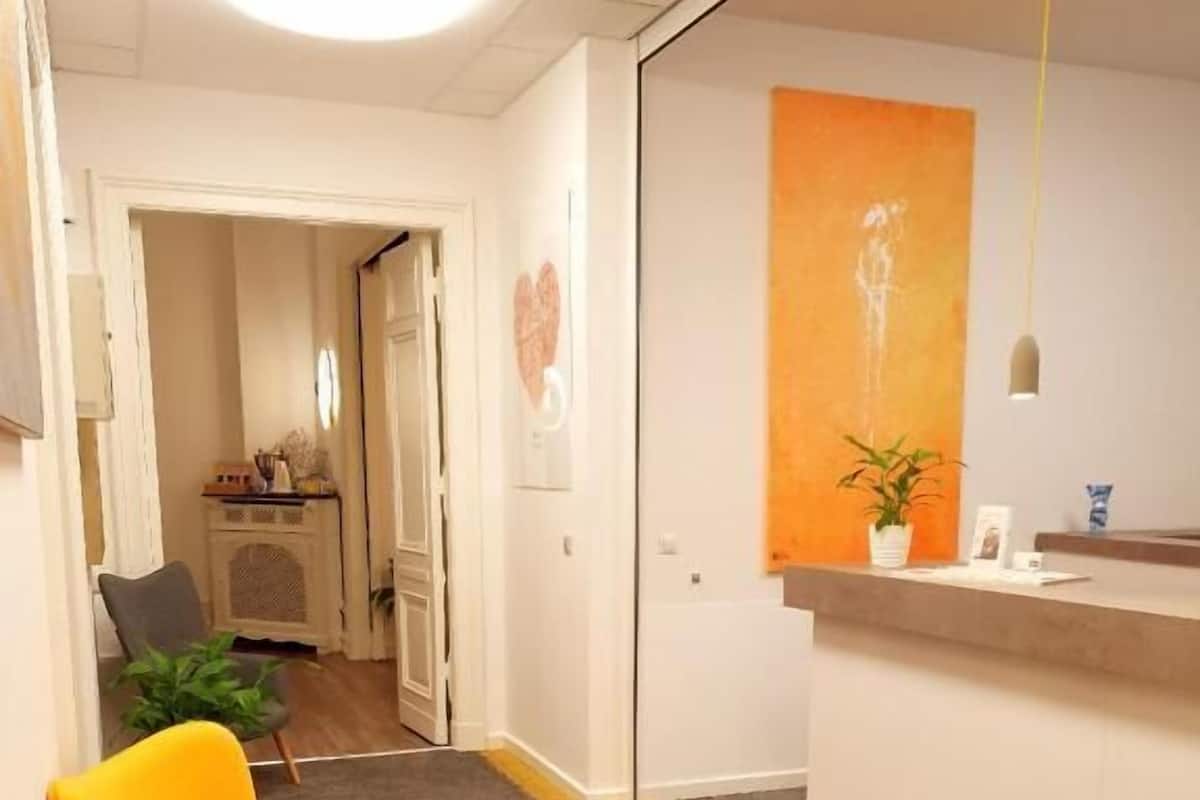 A reception area with a counter, two yellow chairs, a plant, and a carpeted floor.