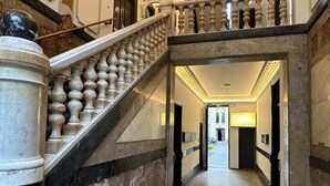 A grand staircase with marble columns and balustrades, leading to a well-lit hallway with a welcoming sign. - Hotel Seifert Berlin am Kurfürstendamm (Berlin)