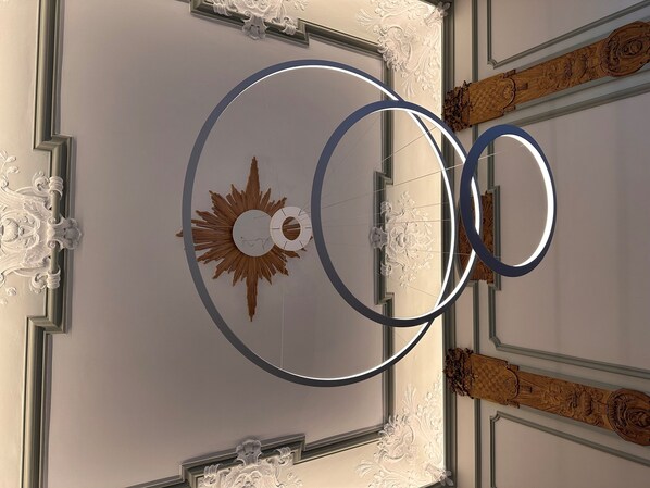 A ceiling with a decorative sun motif, ornate moldings, and a circular light fixture. - Hotel Seifert Berlin am Kurfürstendamm (Berlin)