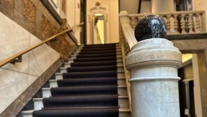 A marble staircase with black carpeted steps, a balustrade, and a spherical object on a column. - Hotel Seifert Berlin am Kurfürstendamm (Berlin)