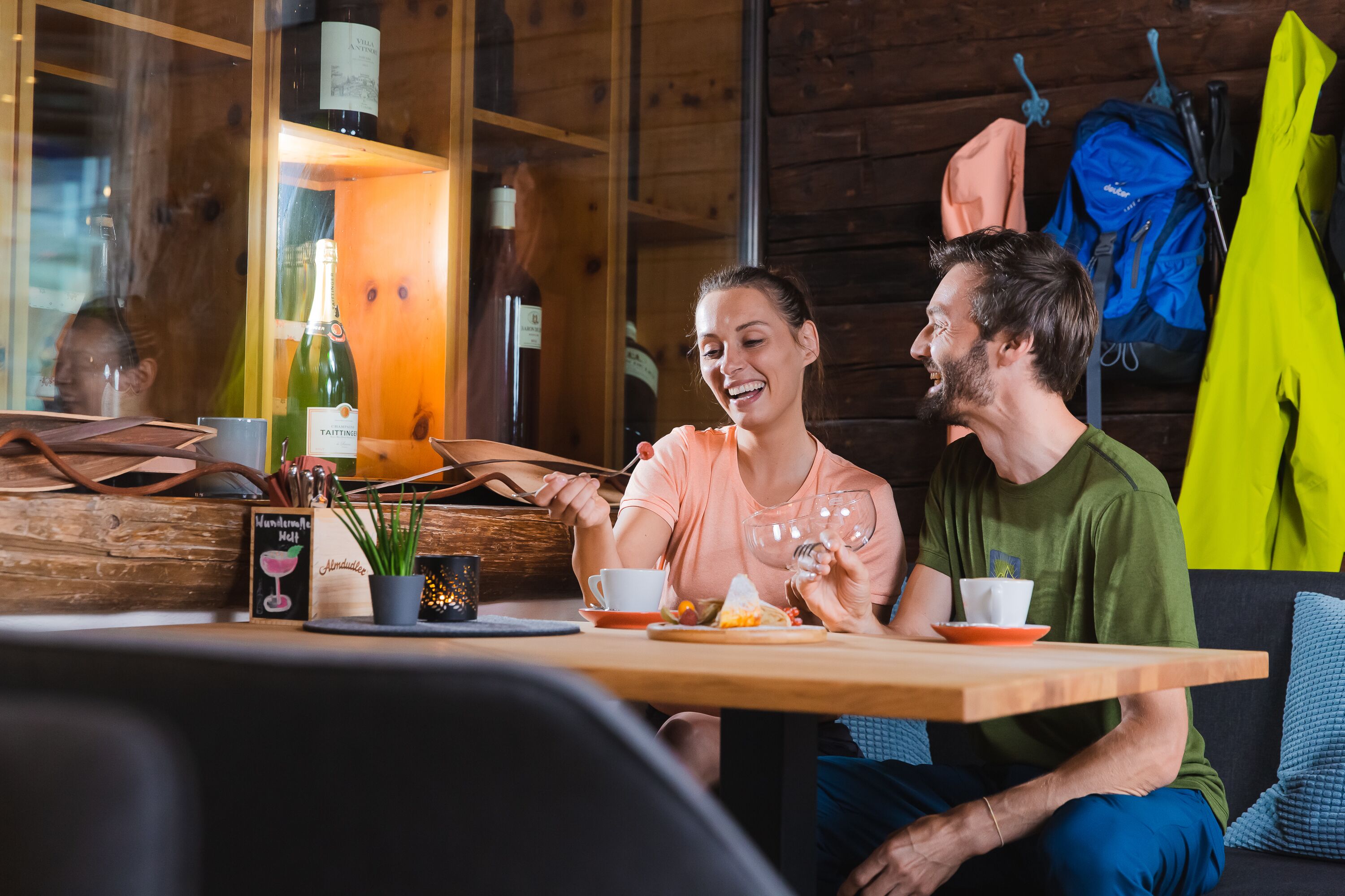 A wooden interior with a table set for two, a wine bottle, and a menu.