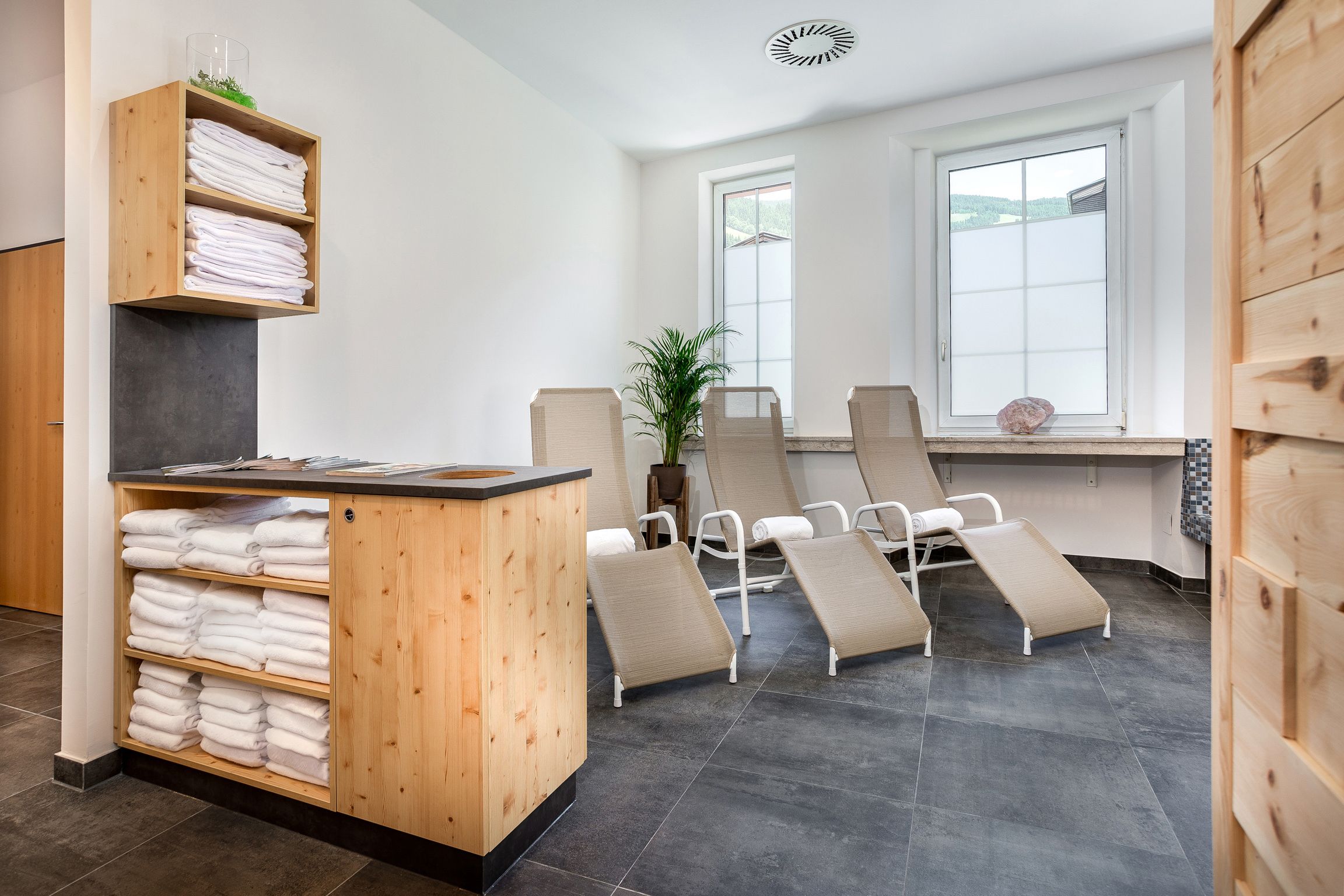 A spa room with a wooden reception desk, multiple towel shelves, and reclining chairs.