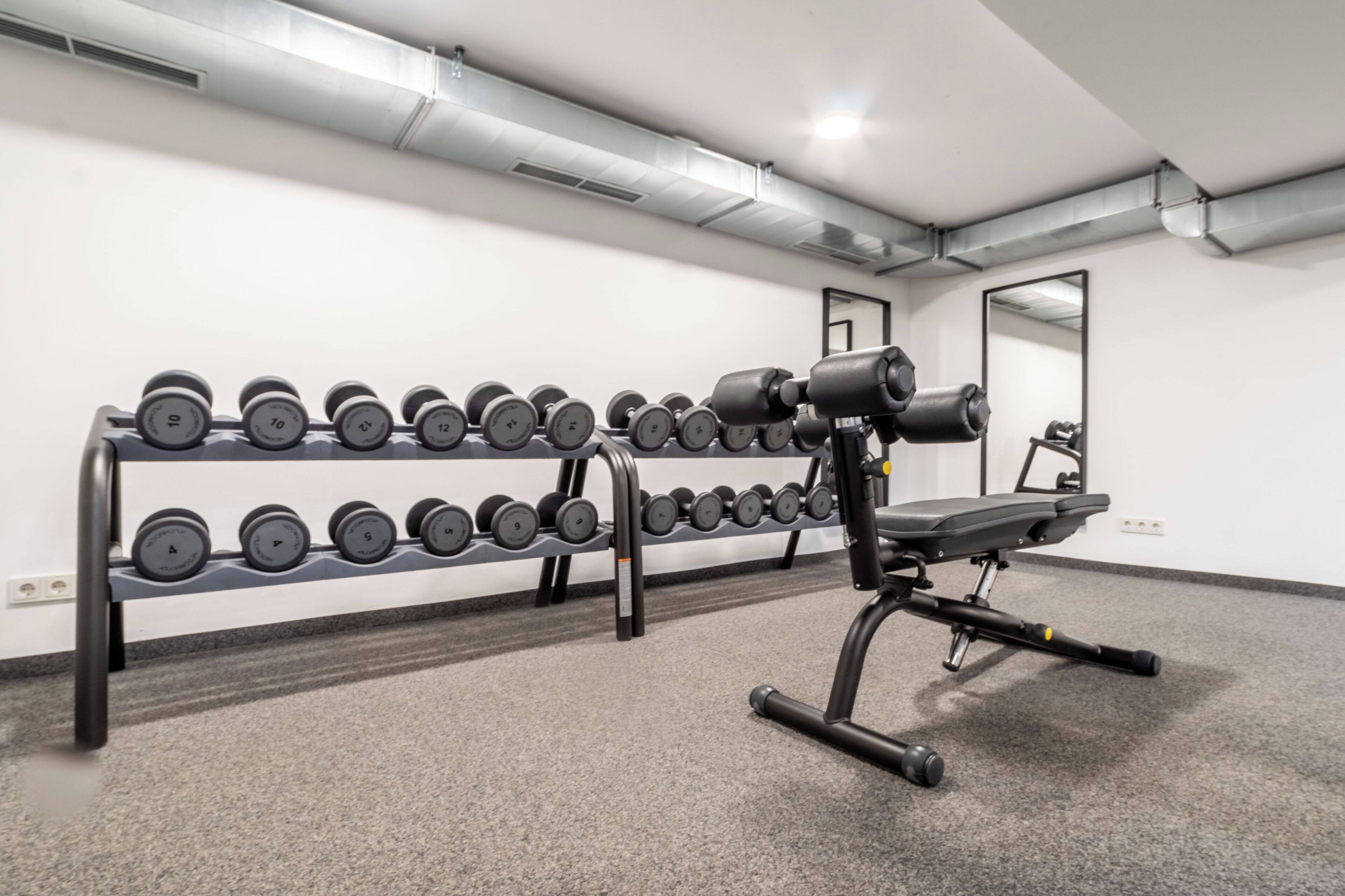 Une salle de sport équipée d’un banc de développé couché et d’une série de haltères.