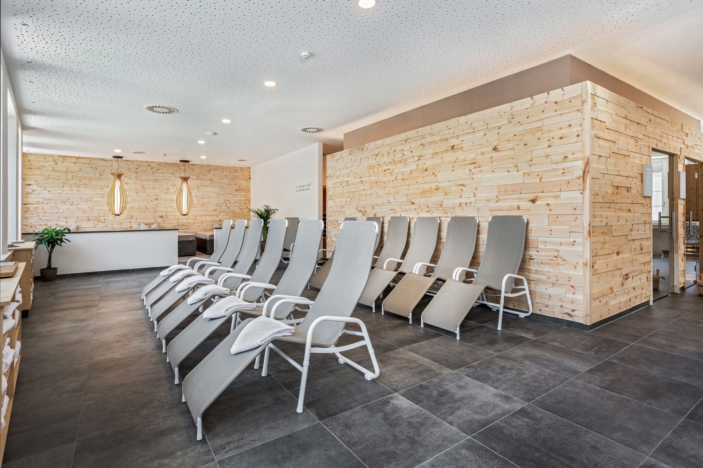 A modern waiting area with a reception desk, wooden panel walls, and rows of chairs.