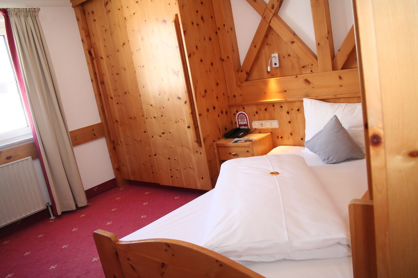 Una habitación con paneles de madera, una cama, una mesita de noche y un radiador.