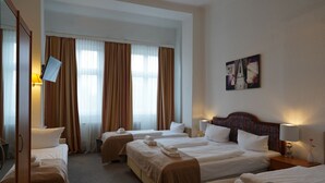 A hotel room with four beds arranged in a U-shape, a large mirror, and a painting on the wall. - City Pension Berlin (Berlin)