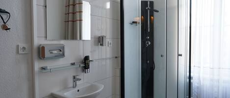 A modern bathroom with a glass-enclosed shower, a white sink, and a mirror above the sink.