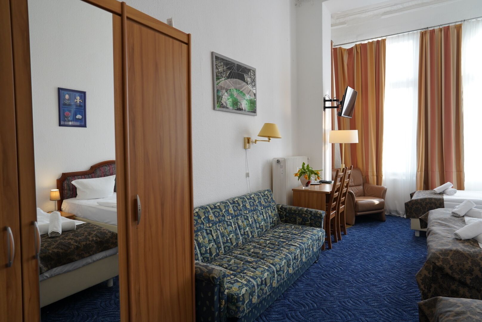 Una habitación de hotel con una cama, un sofá, un escritorio con lámpara y una silla.