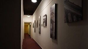 A hallway with a red carpet, white walls, and framed pictures. - City Pension Berlin (Berlin)