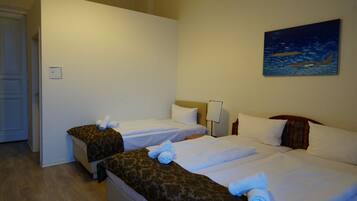 Ein Hotelzimmer mit zwei Betten, einem Bild an der Wand und einer Tür links.