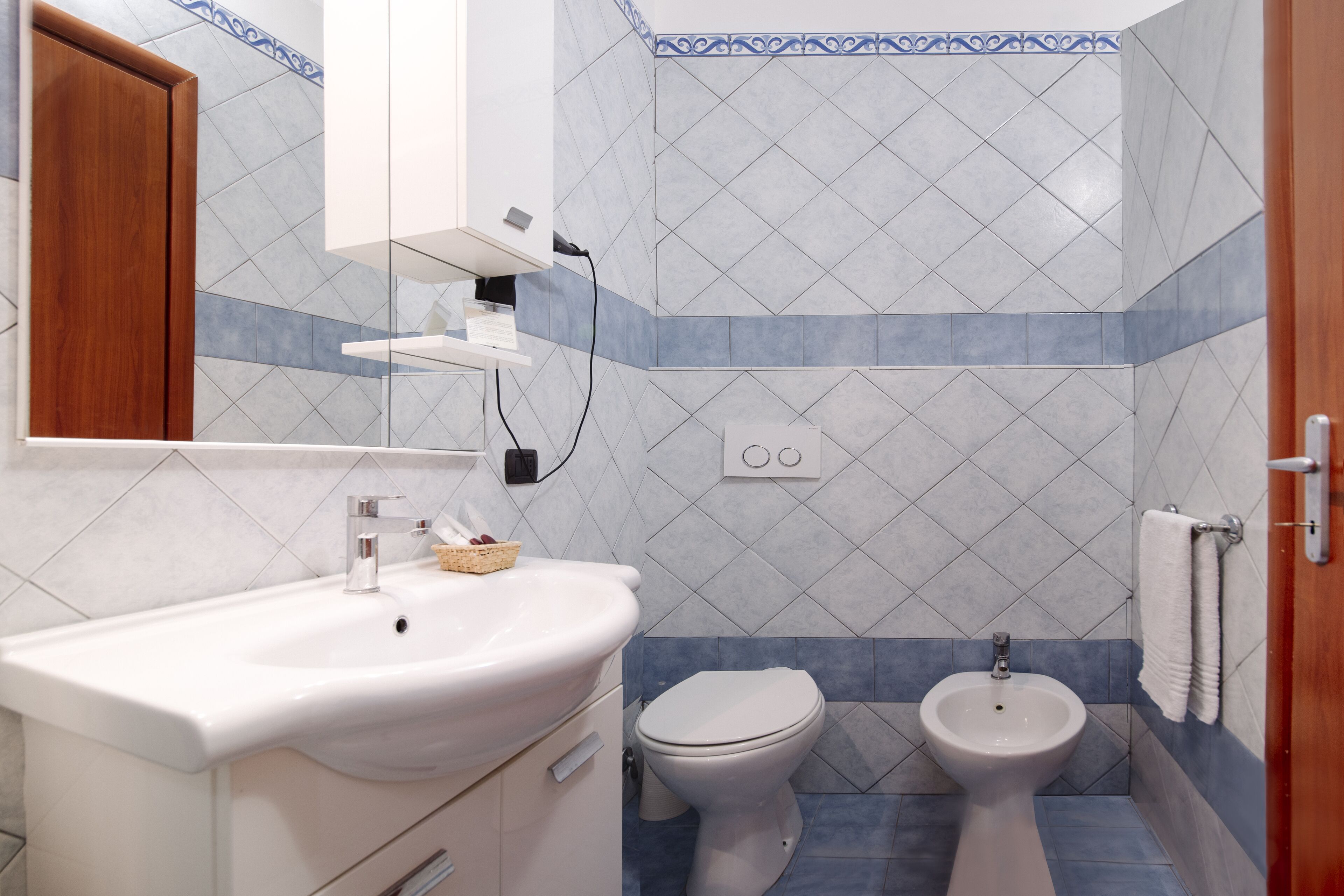 A bathroom with a white sink, a toilet, and a bidet.
