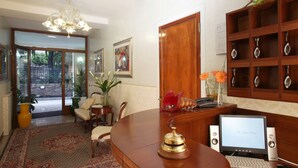A reception area with a wooden desk, a computer, a telephone, and a decorative shelf with items. - Ca' San Rocco (Venice)