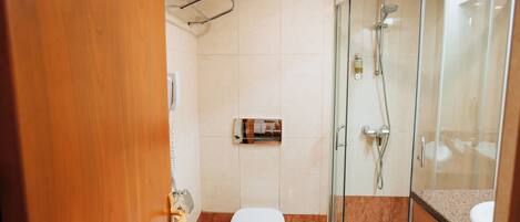 Un bagno moderno con un water, una cabina doccia in vetro e un mobile lavabo in legno.
