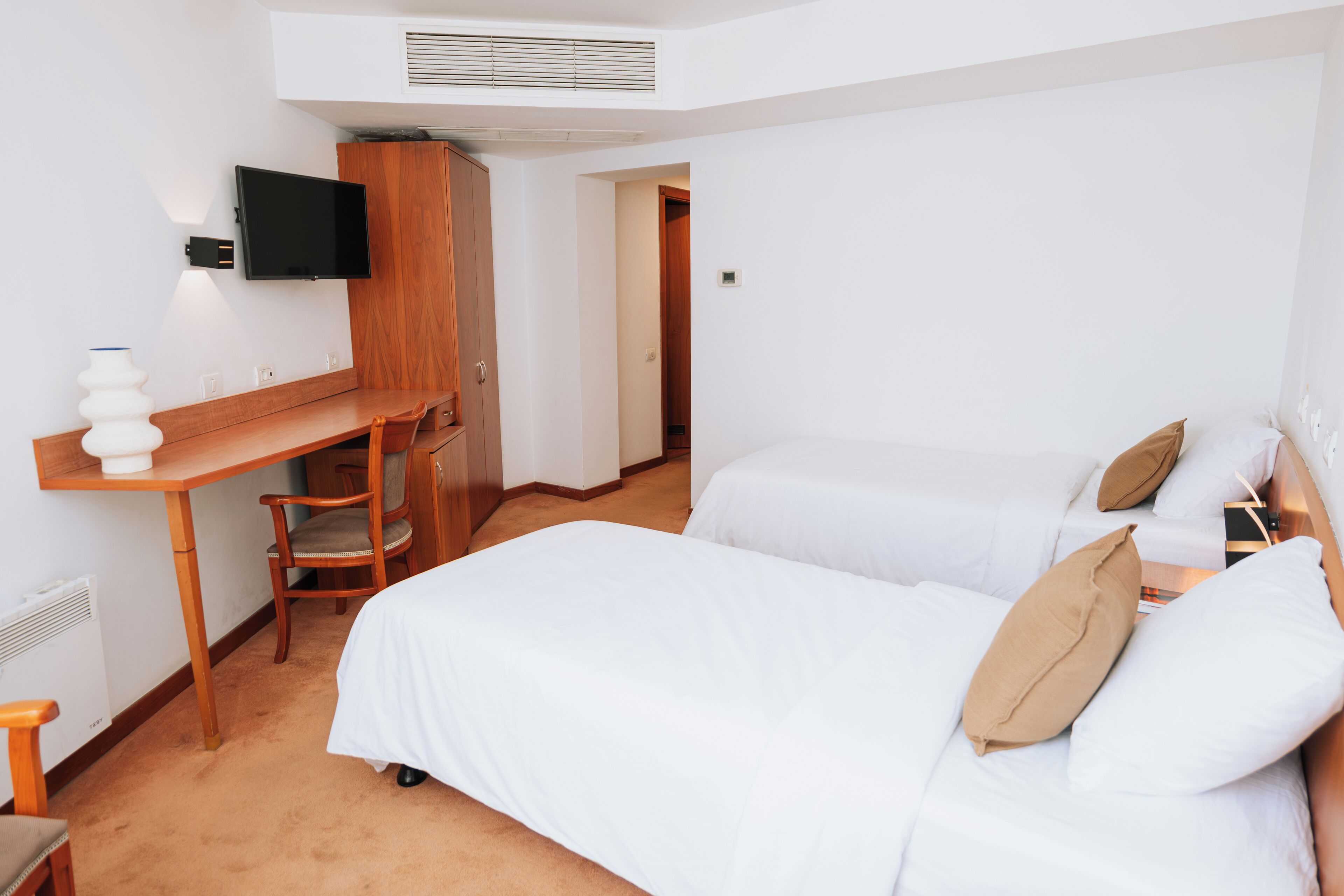 A hotel room with a bed, a desk, a chair, and a television.