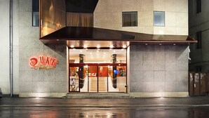 A modern hotel with a unique angular facade, multiple windows, and a Duke logo on the entrance.
