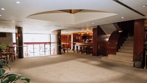 A spacious lobby with a reception desk, seating area, and a staircase leading to upper floors.