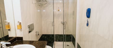 A bathroom with a shower, toilet, sink, and a blue telephone.