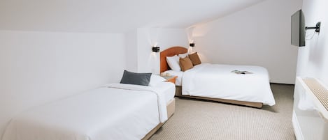 Habitación de hotel con dos camas individuales, tragaluz, televisor de pantalla plana y una mesita con una taza.
