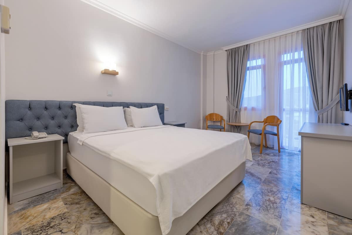 Een hotelkamer met een groot bed, een bureau en een stoel.