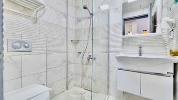 Une salle de bain avec une douche à parois de verre, des toilettes, un lavabo avec un miroir et un porte-serviettes.
