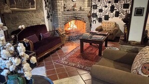 Una sala de estar acogedora con chimenea de piedra, un sofá, una mesa de centro y un jarrón con flores.