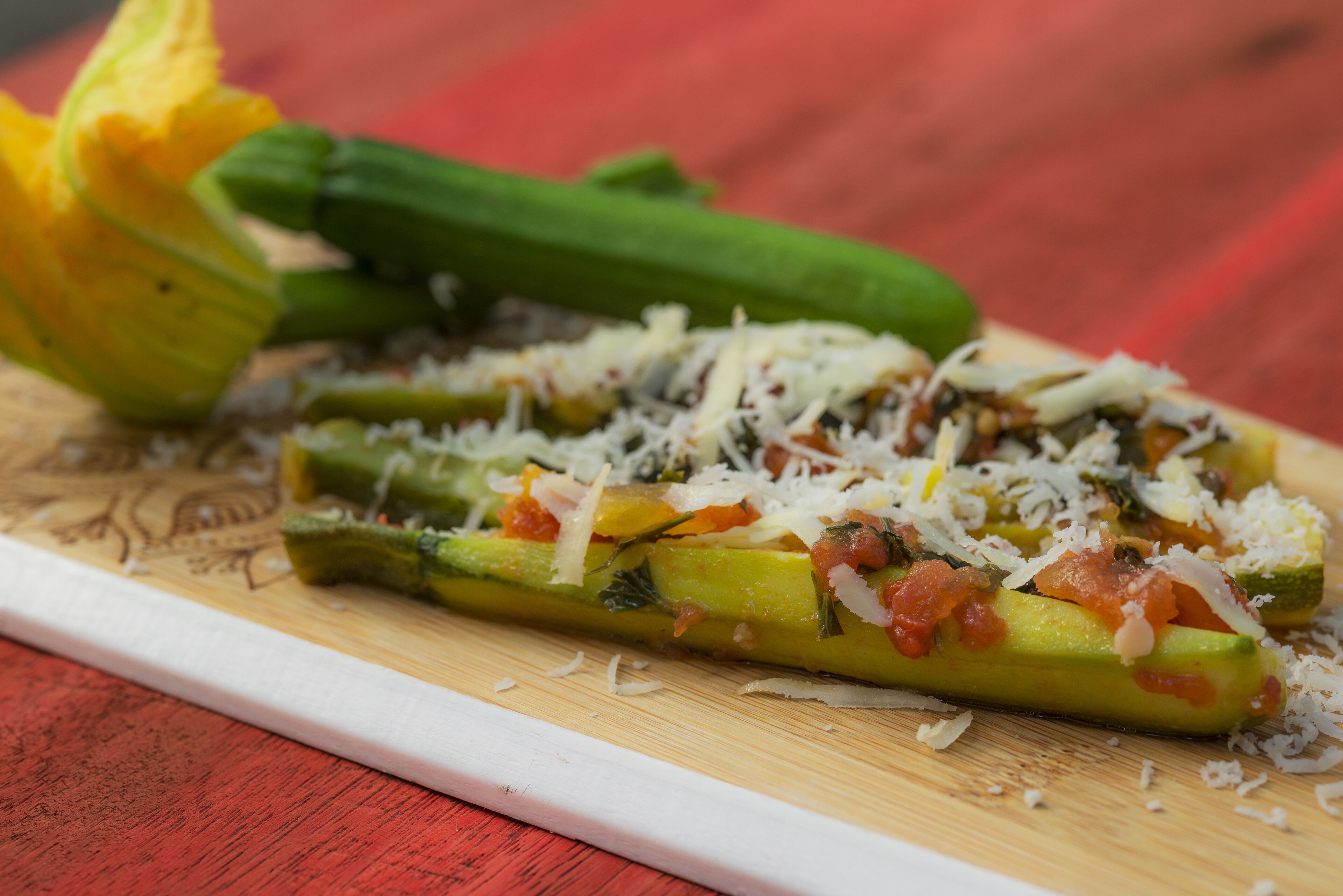 Una tabla de madera con calabacín en rodajas, cubierto de queso y hierbas.