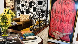 Una habitación con pared de ladrillo, una colección de llaves colgadas, un sofá, una mesa con libros y un cuadro enmarcado.