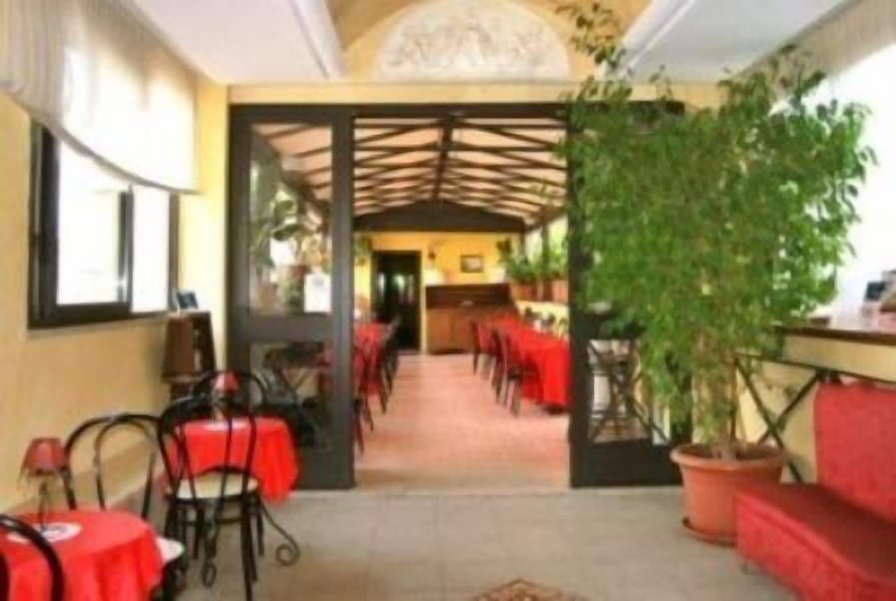 A corridor with tables and chairs, leading to a dining area with a high ceiling and decorative ceiling.