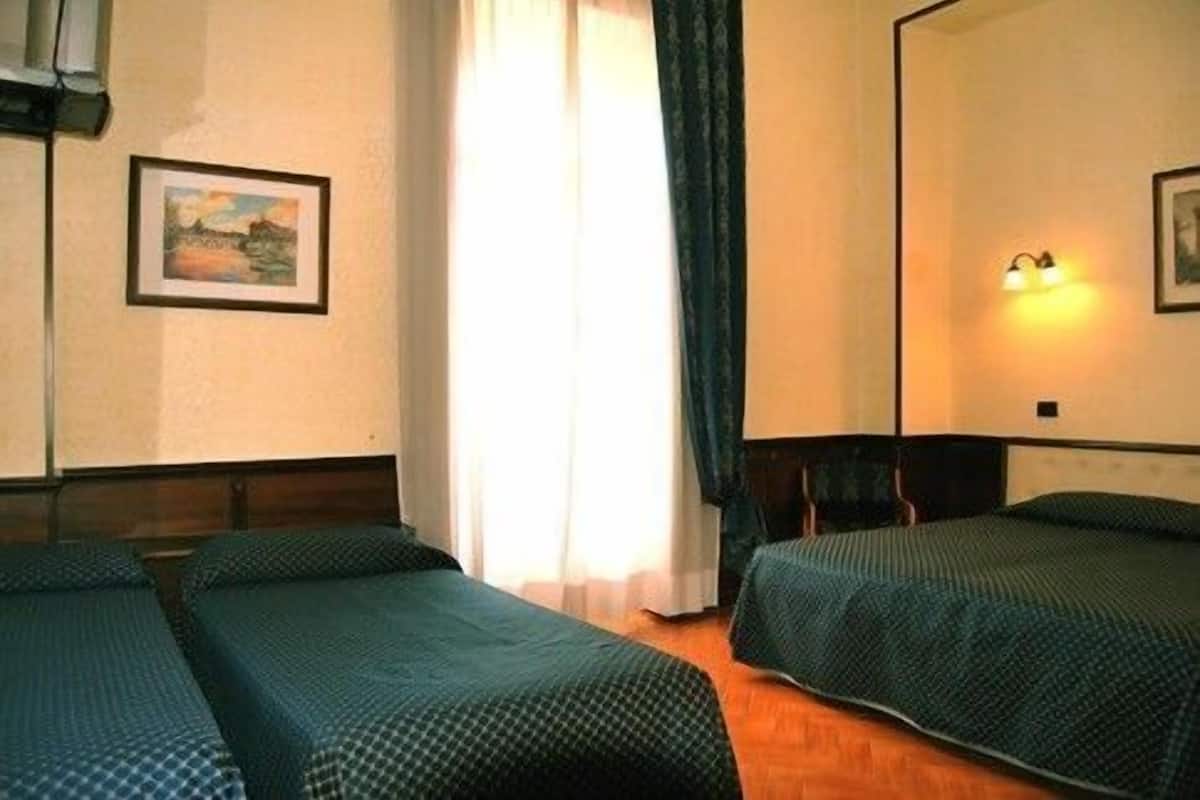Quarto de hotel com duas camas de solteiro, um espelho grande, um quadro na parede e uma janela com cortinas.