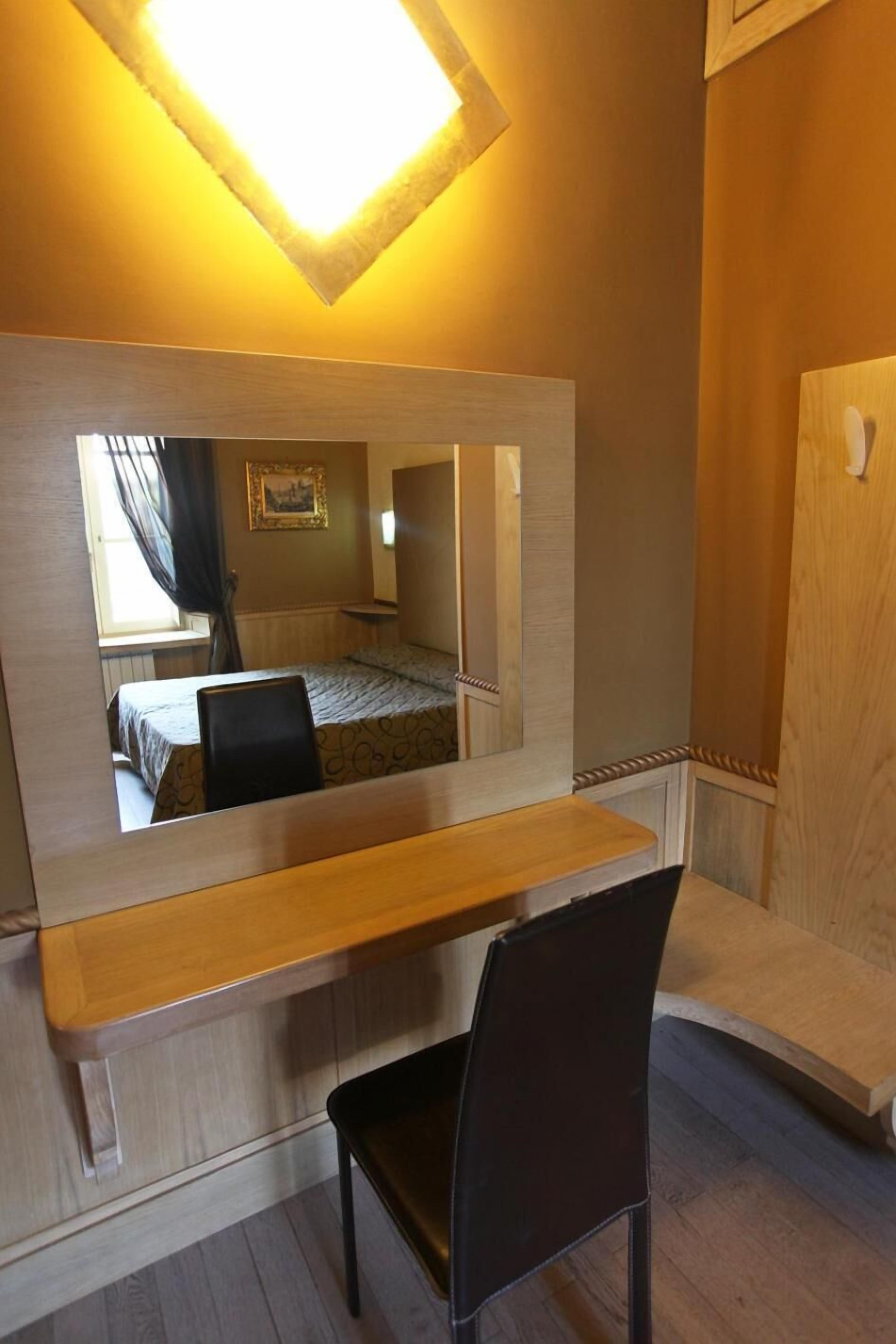 Une pièce comprenant un lit, un bureau, une chaise et un grand miroir.