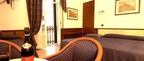 Una habitación de hotel con cama, una silla, una mesa con una botella y vasos, y una puerta que da a un balcón.
