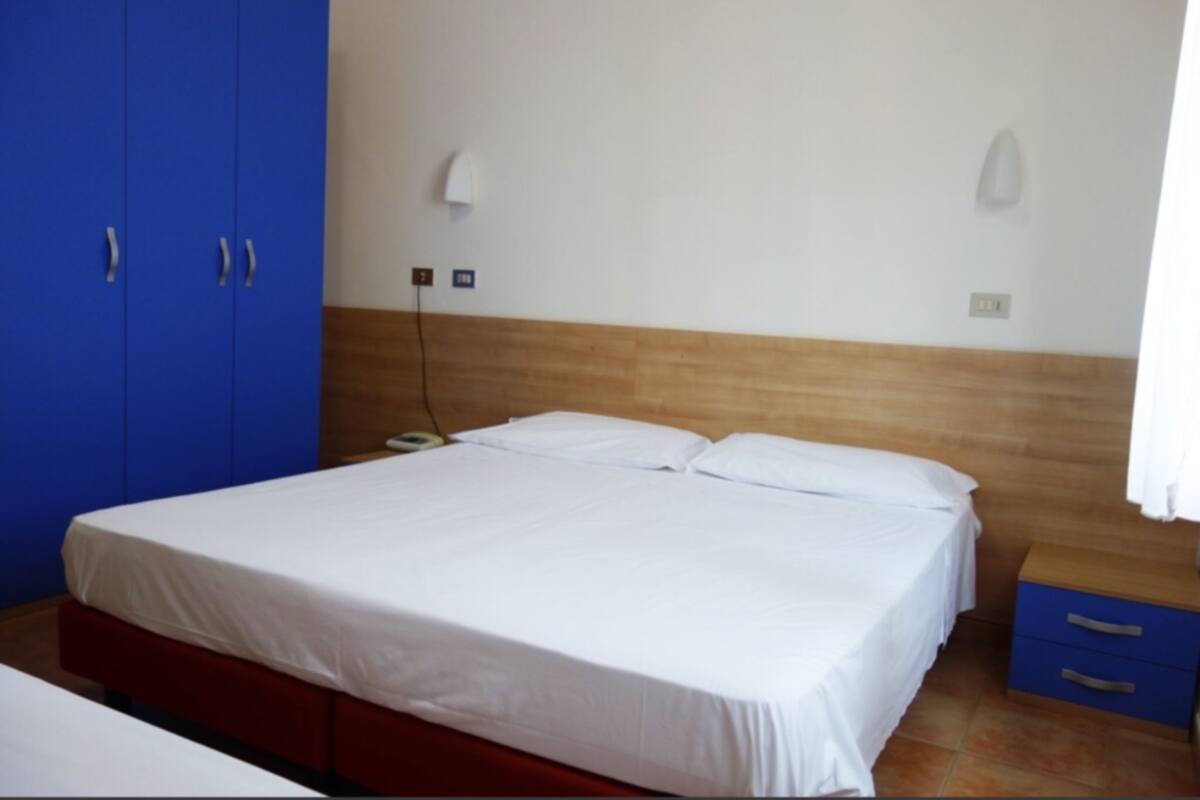Ein Schlafzimmer mit einem Bett, einem blauen Kleiderschrank und einem Nachttisch mit Schubladen.