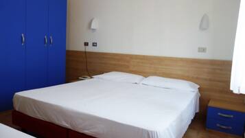 Una camera da letto con un letto, un armadio blu e un comodino con cassetti.