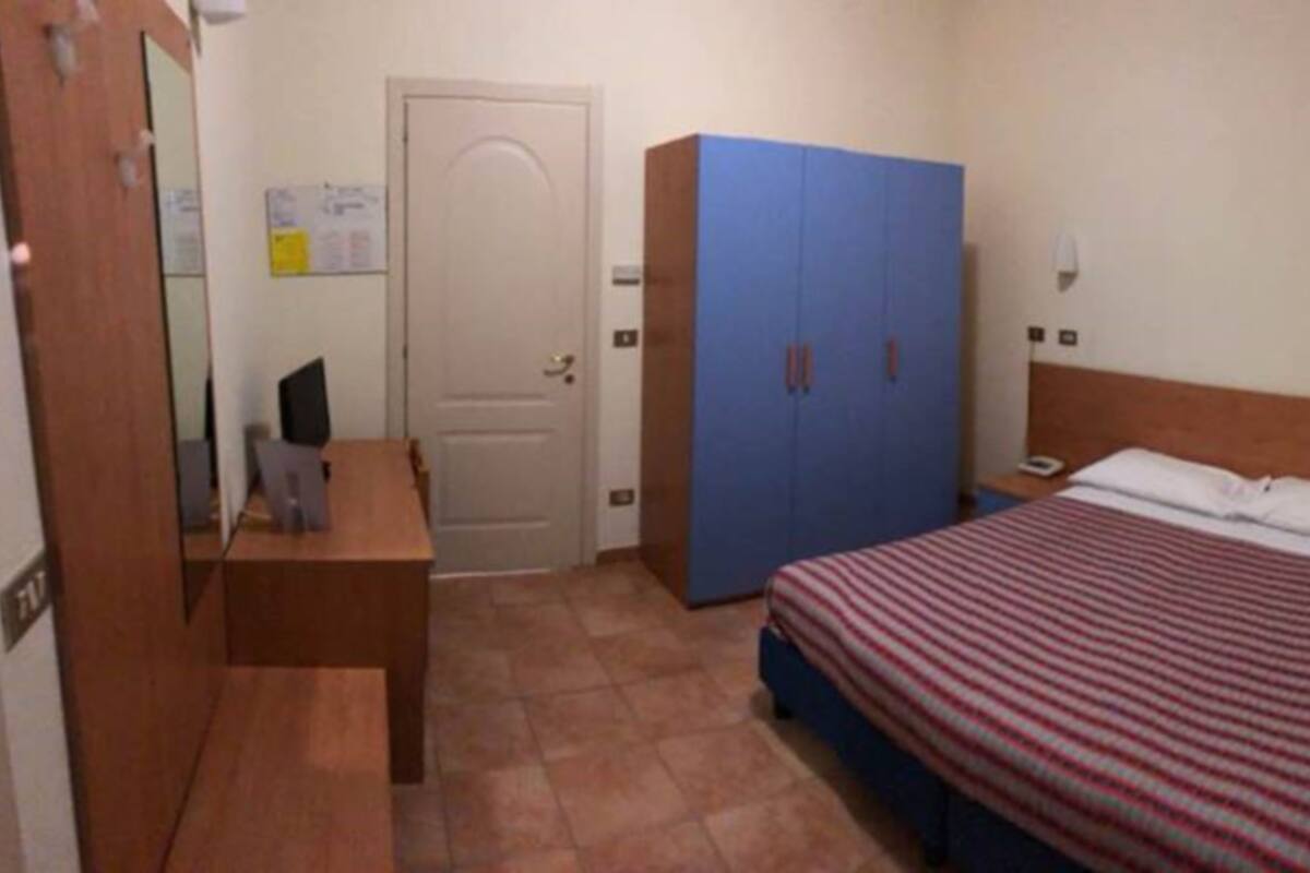 Ein Schlafzimmer mit Bett, Schrank, Schreibtisch und einer Tür.