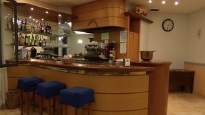 A bar area with stools, a coffee machine, and shelves of bottles. - Serena (Riolo Terme)