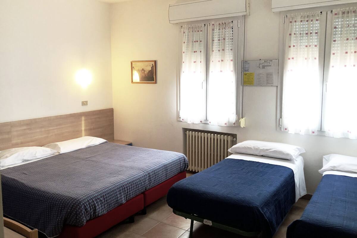 Ein Hotelzimmer mit zwei Betten, einem Heizkörper, einer Wandleuchte und einem gerahmten Bild.